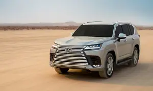 Srebrny Lexus LX 600 przemierza pustynię, unosząc tumany piasku.