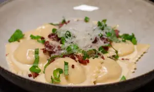 Ravioli salsiccia i krämig sås, toppad med riven parmesan och färska örter. En läcker italiensk rätt.