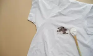 Biała koszulka z ciemną plamą i łyżka sody oczyszczonej. Dowiedz się, jak usunąć żółte plamy z białych ubrań.