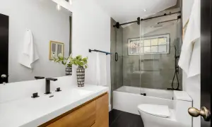 Modernos baños pequeños con lavabo de madera, ducha con mampara de cristal y azulejos grises.