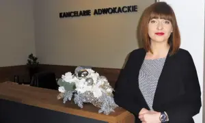 Kobieta w biurze przy recepcji z dekoracją kwiatową.