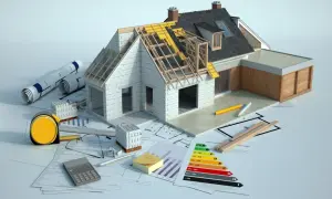 Model domu w trakcie budowy, plany, materiały budowlane i kalkulator. Rozbudowa domu to skomplikowany proces.