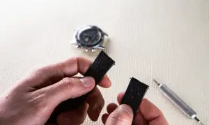 Maintenant, découvrez comment changer un bracelet de montre connectée. Un outil est visible à côté du bracelet noir démonté.