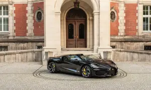 Czarny Bugatti przed pałacem. To auto, z jakiego kraju jest Bugatti, symbolizuje francuską elegancję i moc.