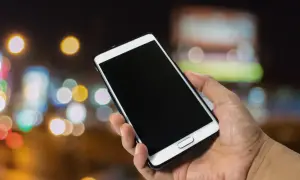 Dłoń trzyma smartfon Samsung. Dowiedz się, jak włączyć telefon Samsung, naciskając przycisk zasilania.
