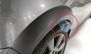 Plastikowa butelka utknęła w nadkole samochodu, tworząc nietypową ozdobę.