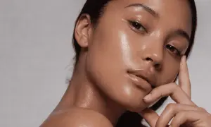 Aha, qué es esa piel radiante y jugosa. Un primer plano de una mujer con un brillo natural en su rostro y cuello.