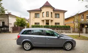 Szary kombi przed domem, symbol dziedziczenia samochodu po ojcu. Jesienne liście na bruku.