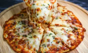 Pyszna pizza z tortilli z ciągnącym się serem i ziołami, podana na drewnianej desce.