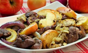 Pyszna wątróbka z jabłkiem, cebulą i grzybami na białym talerzu. Aromatyczne danie, które zachwyci każdego smakosza.