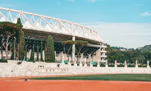 Stadion w Rzymie z rzędami rzeźb i zielenią.