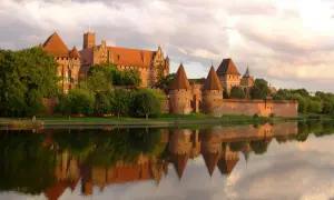 Malbork, jeden z największych zamków w Europie, odbija się w spokojnej wodzie.