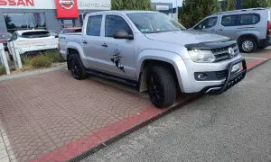 Srebrny pickup z naklejką kompasu i postacią, gotowy do podróży. Idealny do pkd wynajem samochodów.