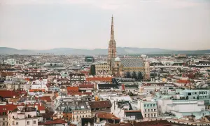 Ein atemberaubender Blick auf Wien von oben. Der Stephansdom mit seinem markanten Turm und dem bunten Dach dominiert die Stadtansicht.