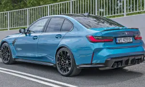 Niebieskie BMW M3 z czarnym spoilerem i dyfuzorem, na sportowych felgach, gotowe do jazdy.