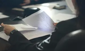 Osoba przegląda dokumenty, analizując pozaszkolne formy edukacji PKD.