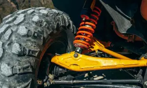 Gros plan sur la jambe de force voiture, avec son amortisseur orange vif et son pneu tout-terrain. Le bras de suspension jaune vif est prêt pour l'aventure.