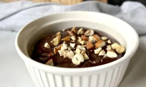Czekoladowy deser low carb posypany orzechami w białej miseczce.