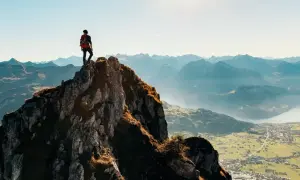 Wspinacz na szczycie skalistej góry, podziwiający panoramę. Czy wejście na rysy jest trudne? Widok zapiera dech w piersiach.