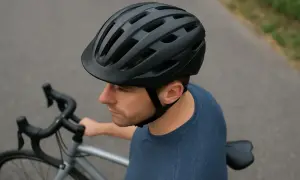 Mężczyzna w czarnym kasku rowerowym, gotowy do jazdy. Czy kask jest obowiązkowy? Zawsze warto go mieć!