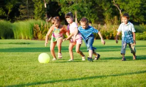 Niños jugando a la pelota en el césped, disfrutando de divertidos juegos con pelotas para niños al aire libre.