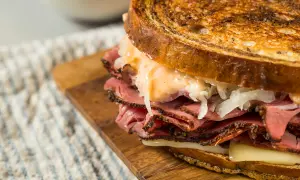 Un delicioso bocata de pastrami con pan tostado, queso fundido y chucrut.