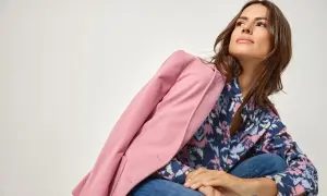 Kobieta w dżinsach i wzorzystej koszuli, narzucony różowy żakiet. Stylizacja w stylu color blocking.