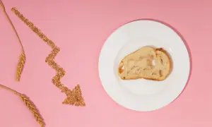 Strzałka z ziaren pszenicy wskazuje na kromkę chleba na talerzu, symbolizując nietolerancję glutenu i dietę bezglutenową.