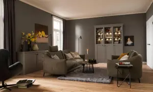 Ein weicher, grauer Teppich liegt unter dem Sofa und dem Couchtisch und schafft eine gemütliche Atmosphäre im Wohnzimmer.