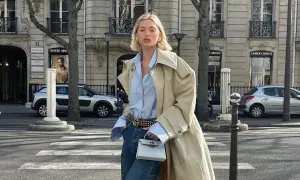 Elegancka kobieta w beżowym trenczu, błękitnej koszuli i jeansach, prezentująca stylowy sposób, jak nosić trencz. Paryskie uliczne klimaty.