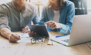 Para uchronić się przed oszustwami związanymi z kredytem na PESEL, para analizuje dane na tablecie i laptopie.