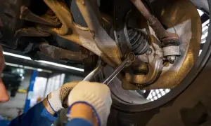 Mechanik dokręca śrubę w wielowahaczu samochodu.