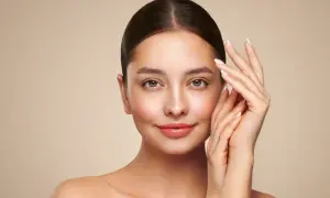 Portret kobiety z gładką cerą i dłońmi delikatnie dotykającymi twarzy.