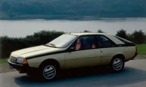 Złoty Renault Fuego z czarnymi pasami na boku, zaparkowany nad jeziorem.