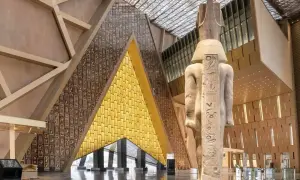 Wielki posąg faraona w nowoczesnym muzeum egipskim. Ściany zdobią hieroglify i złote panele.