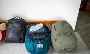 Drei Rucksäcke bereit für das Abenteuer. Ein schwarzer Lowepro, ein blauer mit Regenhülle und ein grüner Porter 65 – perfekt für das Asien Backpacking.