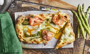 En läcker pizza med rökt lax, ägg och sparris, som en italiensk dröm på en tallrik.