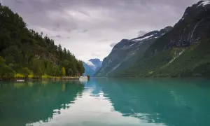 Turkusowa woda odbija góry i lasy. Statek czeka na pasażerów na wycieczkę po fiordach norweskich.