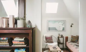 Accogliente libreria in mansarda con un letto, una poltrona e un quadro.