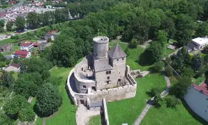 Zamek w Będzinie, majestatyczna warownia z kamienia, góruje nad zielonym krajobrazem.