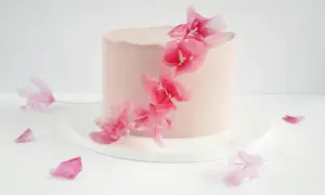 Różowy tort ozdobiony delikatnymi, różowymi kwiatami z masy cukrowej. Inspiracja do stworzenia własnych kwiatów z masy cukrowej krok po kroku.