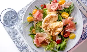 En härlig sallad med prosciutto, krämig ost med nötter, körsbärstomater och gröna blad. En perfekt sommarrätt.