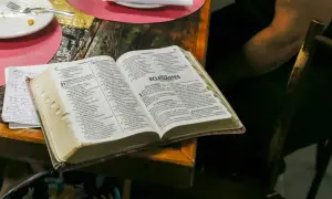 Co Biblia mówi o spowiedzi? Otwarta Biblia na stole, obok talerz i notatki.