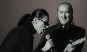 Kora śpiewa do mikrofonu, a obok niej gra na gitarze muzyk. To scena z koncertu, gdzie można usłyszeć maanam piosenki alfabetycznie.