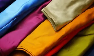 Bunte Stoffbahnen, die an die Viskose Herstellung erinnern. Leuchtende Farben wie Blau, Lila, Gelb und Grün sind übereinandergelegt.