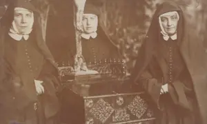 Trzy zakonnice w habicie, obok ołtarzyka z krucyfiksem. Wśród nich może być święta Kornelia.