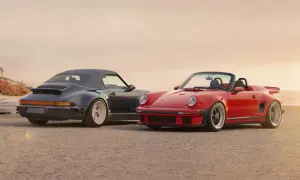 Dos Porsche descapotables, uno rojo y otro azul oscuro, posan en la playa. El **Singer Porsche** rojo destaca con su diseño deportivo y el azul con su capota puesta.
