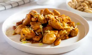 Un invitante piatto di pollo alle mandorle, lucido e saporito, guarnito con erba cipollina.