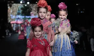 Niñas desfilan con trajes de flamenca, mostrando cómo vestir a un niño de flamenco con flores y mantones.