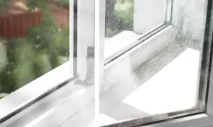 Porysowana szyba w oknie, z widocznymi licznymi zadrapaniami, kontrastuje z czystą ramą okienną.